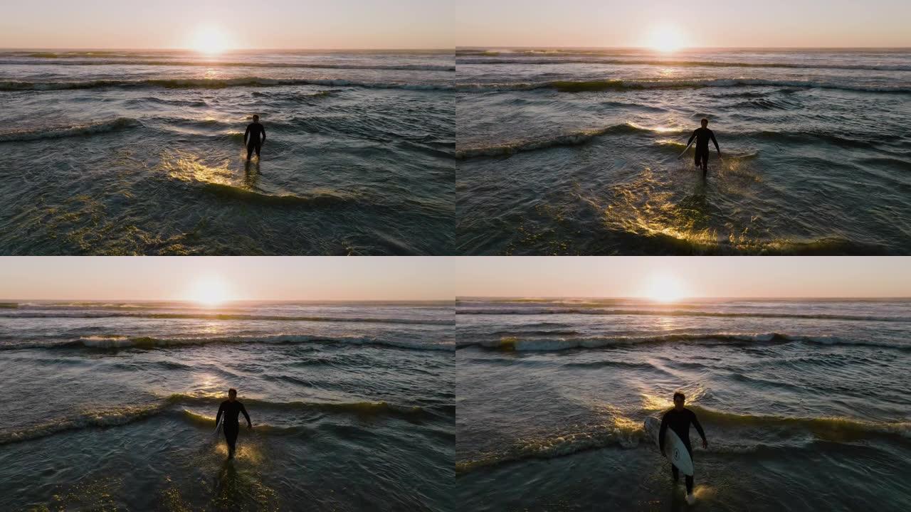 冲浪者走出大海的空中背光日落景色