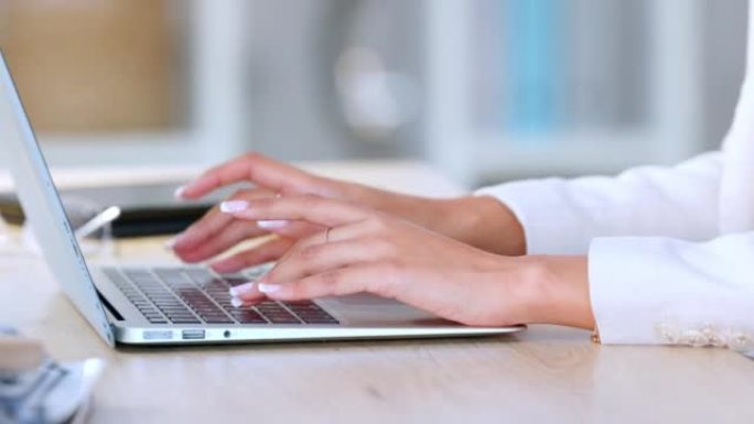 在办公室工作时，手在电脑上打字的美丽指甲特写。年轻的现代数字设计师与网络上的同事合作。一位公司女性写