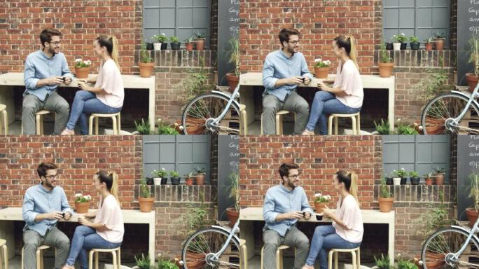 4k视频片段，一对年轻夫妇在约会期间一起坐在咖啡馆外面