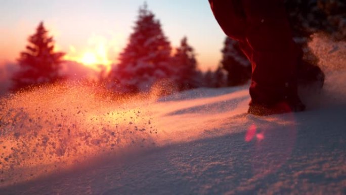 特写: 无法辨认的女性游客在日出时踩着深深的粉末雪。