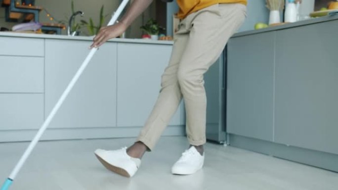 快乐的年轻人做家务洗地板，戴着现代耳机跳舞