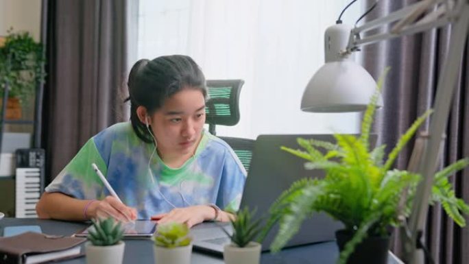 亚洲少女在家在线学习时使用平板电脑。