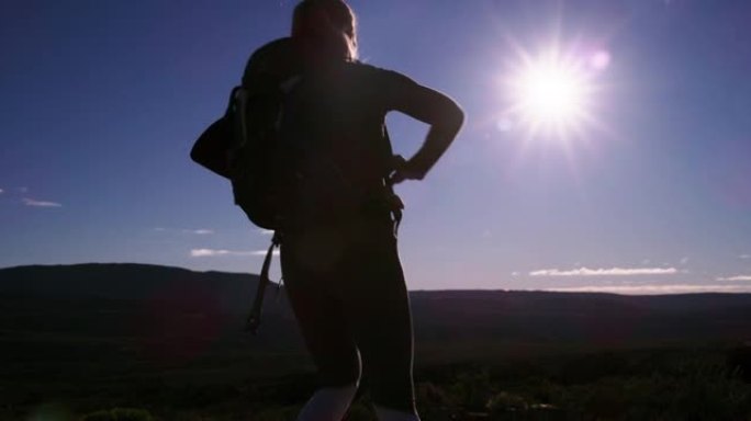 4k视频片段，一名年轻女子举起手臂，看着山上的风景