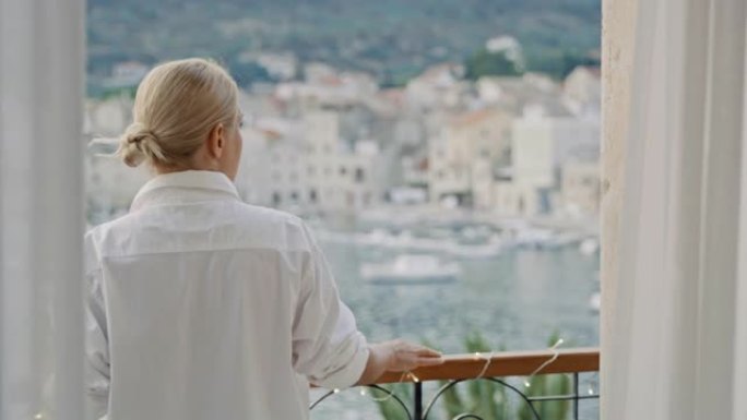 穿着白衬衫的SLO MO女人走到海边的阳台上