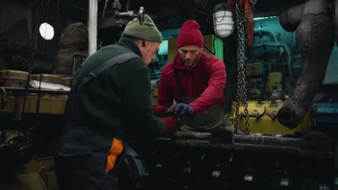 成年男子帮助同事修理船舶发动机