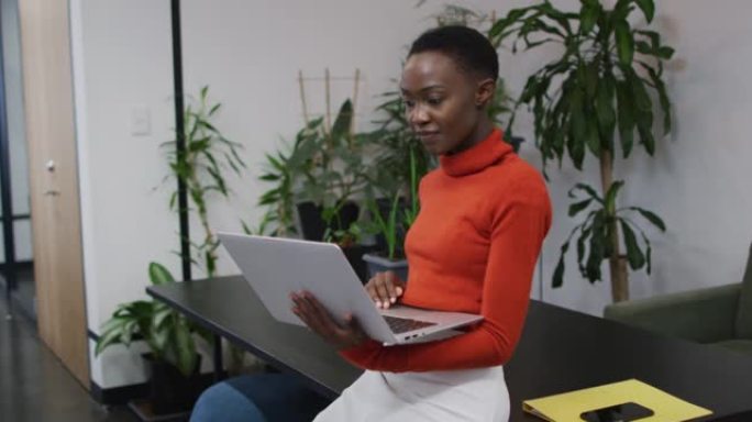 非裔美国妇女在办公室使用笔记本电脑时微笑的肖像
