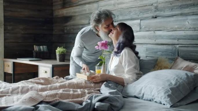 可爱的男人把早餐带到床上给幸福的女人亲吻微笑享受早晨在家
