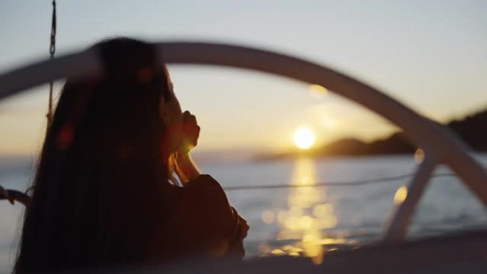 LS ZI孤独的女人坐在日落时航行的帆船甲板上