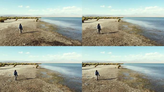 亚洲摄影师沿着湖岸散步，看着风景