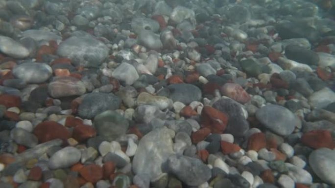 海浪到来后，相机浸入水中。在圆石滩上拍打海浪的慢动作镜头。海洋自然背景
