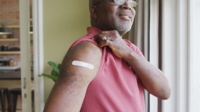 非裔美国高级男子的肖像在家里展示了他接种疫苗的肩膀