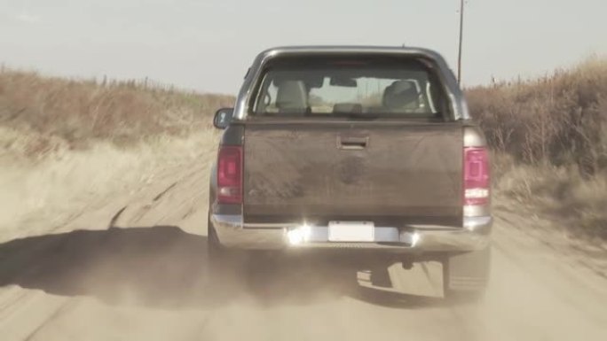 皮卡车在阿根廷尘土飞扬的乡村道路上加速行驶。4k分辨率。