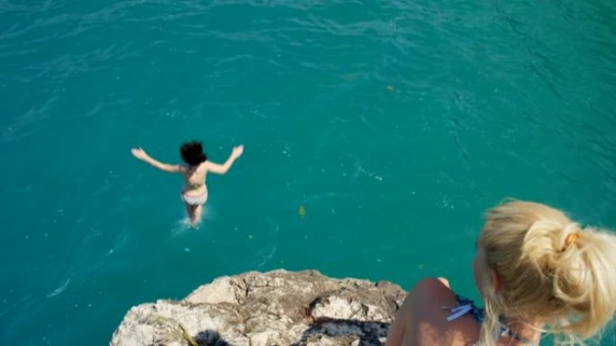 4k视频片段，一名年轻女子从悬崖上跳入大海