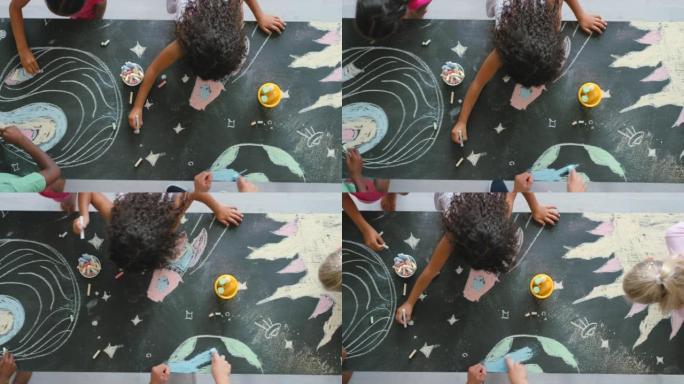 富有创造力的幼儿在黑板上用粉笔绘画和制作彩色的空间图片。上面是孩子们给行星和恒星着色的视图。艺术学生
