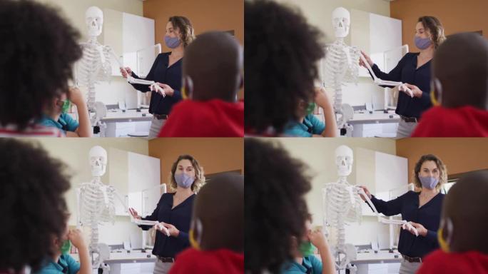 女教师戴口罩用人体骨骼模型上课教学生