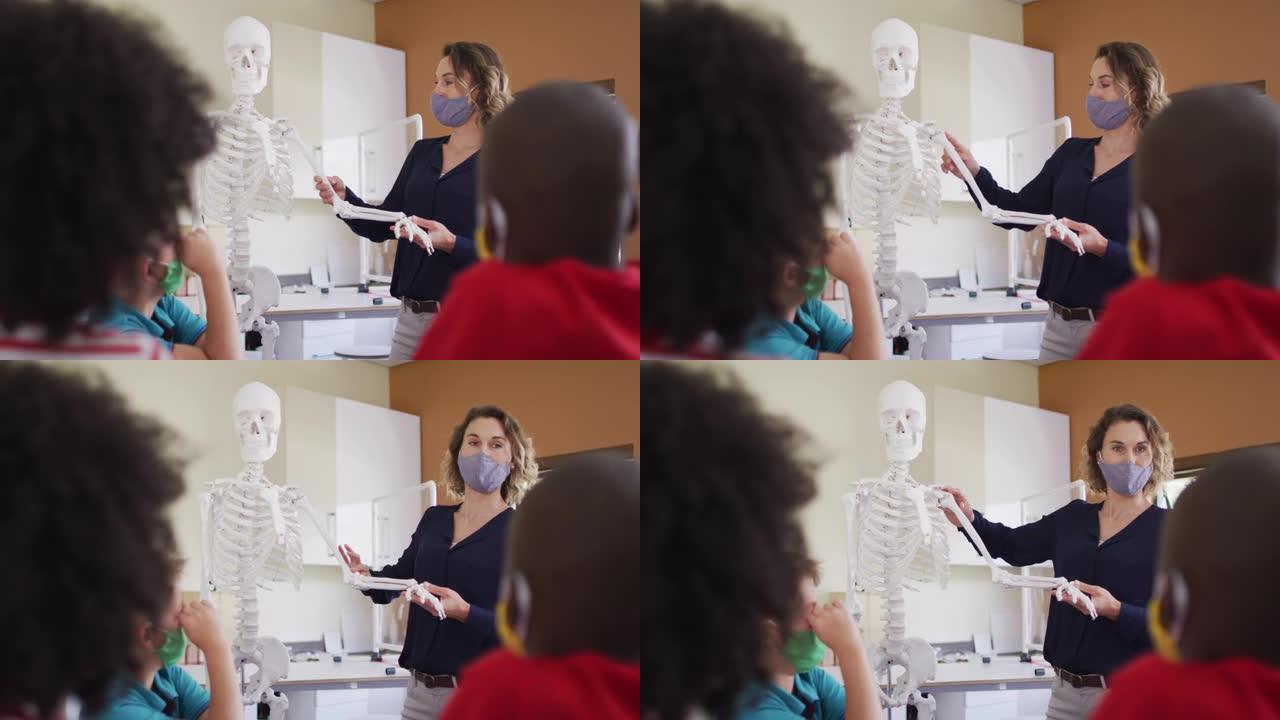 女教师戴口罩用人体骨骼模型上课教学生