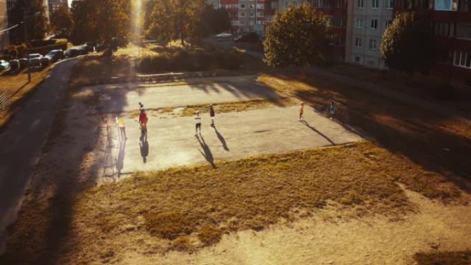 附近朋友在城市后院外面踢足球的空中无人机拍摄。多元文化的孩子们在郊区一起踢足球。快乐的童年和运动理念