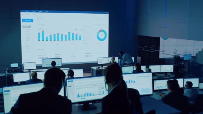 专业交易员在现代监控办公室工作，在大屏幕上提供实时分析供稿。经纪人和金融专家的监控室坐在电脑前。