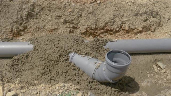 特写: 新鲜混凝土覆盖塑料污水管在夏天的阳光下干燥。