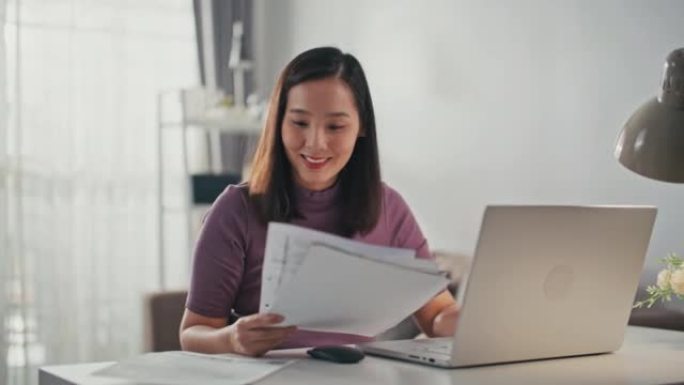 亚洲妇女在家中使用笔记本电脑在线支付账单