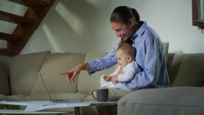 一位幸福的母亲和她刚出生的婴儿的真实照片正在笔记本电脑上观看视频