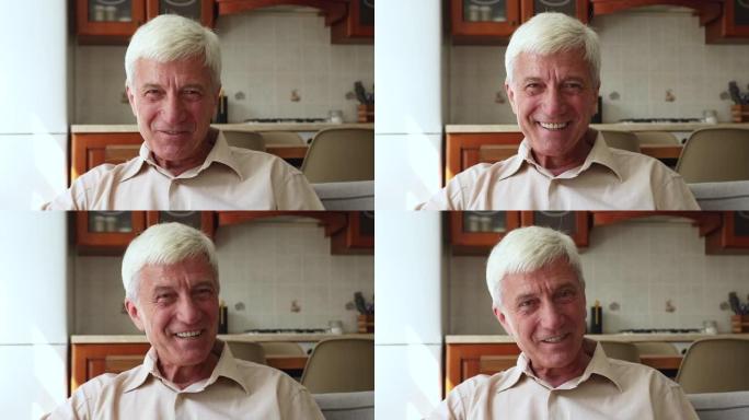 年龄较大的白发男子微笑着用视频会议看着摄像机说话