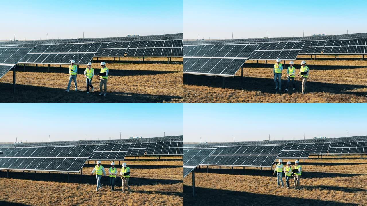 三位工程师在太阳能发电站讨论商业问题。替代能源，可再生电力概念。
