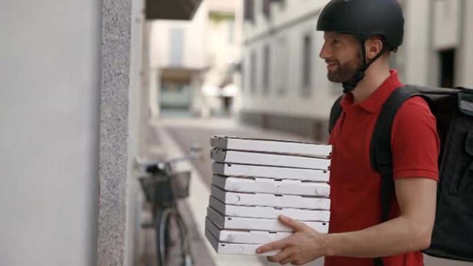 一位年轻的带背包和头盔的微笑披萨快递员正在每天在市中心直接向客户发送订单。