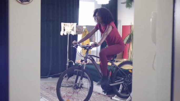 非裔美国女士正在家里骑自行车练习