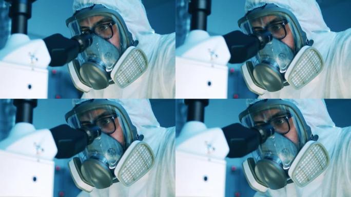 身穿危险品套装的实验室专家正在显微镜下观察