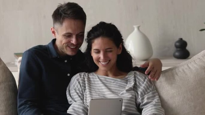 幸福的年轻夫妇在家里使用数字平板电脑。