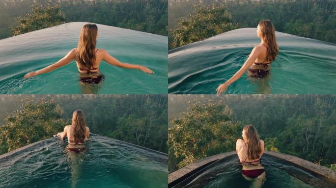 性感的女人在游泳池散步，享受异国情调的暑假在酒店水疗中心享受奢华的生活方式，日出时可以看到热带丛林