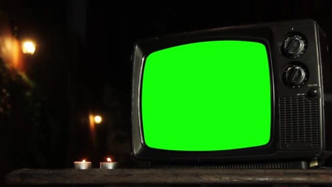 复古电视绿屏在晚上与蜡烛。