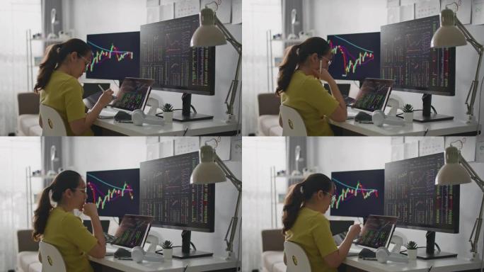 亚洲妇女在电脑上在家工作，同时交易股票市场并计算收益。
