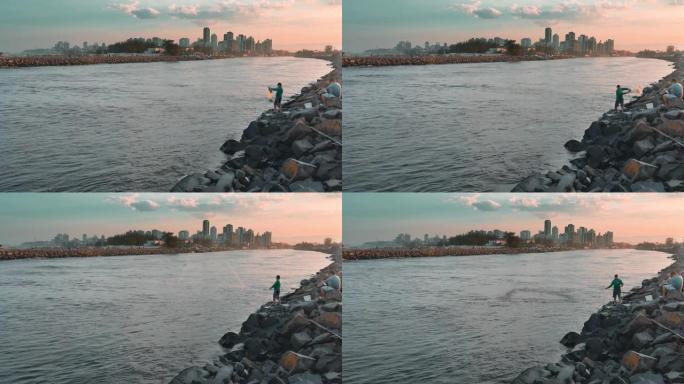 巴西圣卡塔琳娜州Passo de Torres海滩，男子在日落时将渔网扔进河中