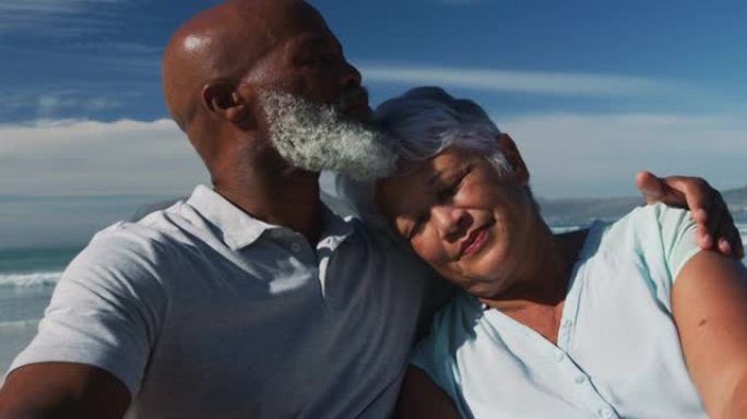 快乐的资深非裔美国夫妇坐在沙滩上拥抱