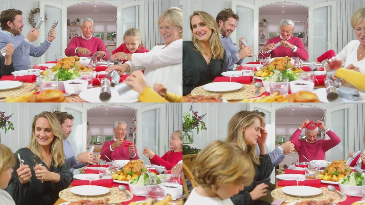 多代家庭在家里吃圣诞大餐前拉饼干，戴上纸帽