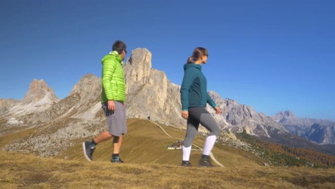 慢动作: 健康的高加索夫妇沿着俯瞰Passo Giau的小径远足。