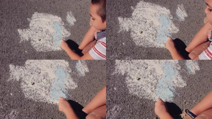 小男孩用粉笔在沥青路面上画画