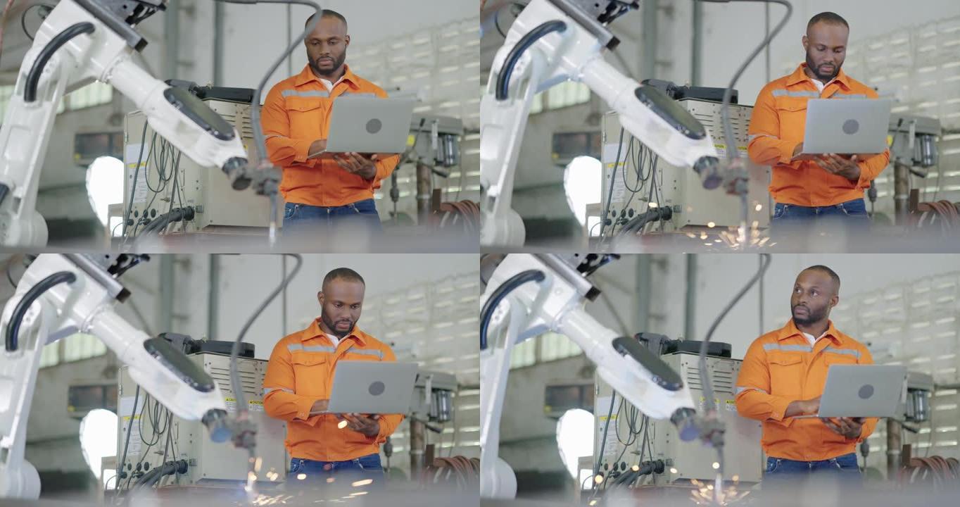 30岁的非裔美国人青年工程师通过计算机对智能工厂工业中的机器人自动臂机进行检查和控制。机器人，科学技