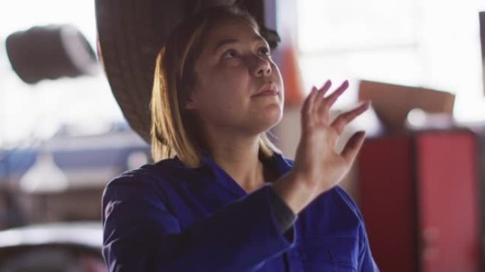 女机械师使用数字平板电脑并在汽车服务站检查汽车