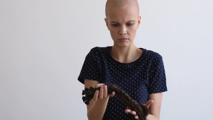 秃头女孩癌症患者拿着辫子堆感到困惑