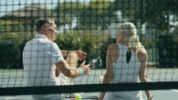 比赛结束后，成熟的夫妇坐在网球网后面说话和建立联系