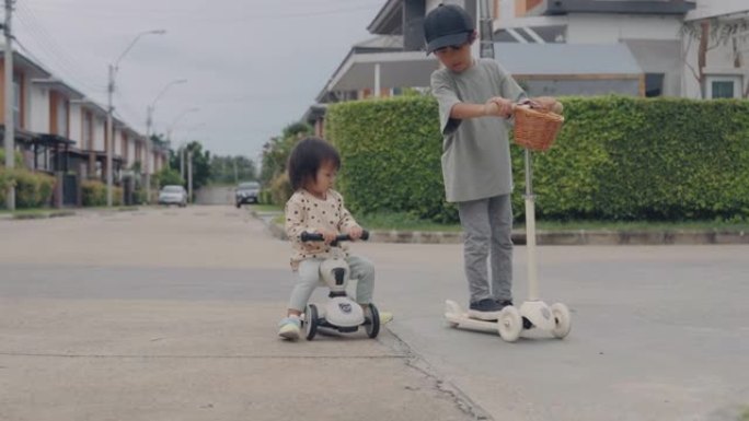 小男孩和他的妹妹骑着一辆踏板车。