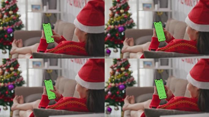 女人使用带有绿屏的智能手机，圣诞节网购的概念