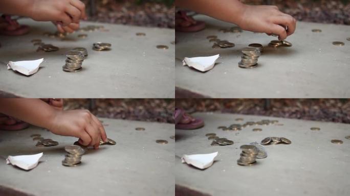 一个小女孩的手在户外从她破碎的存钱罐里收集硬币。特写。