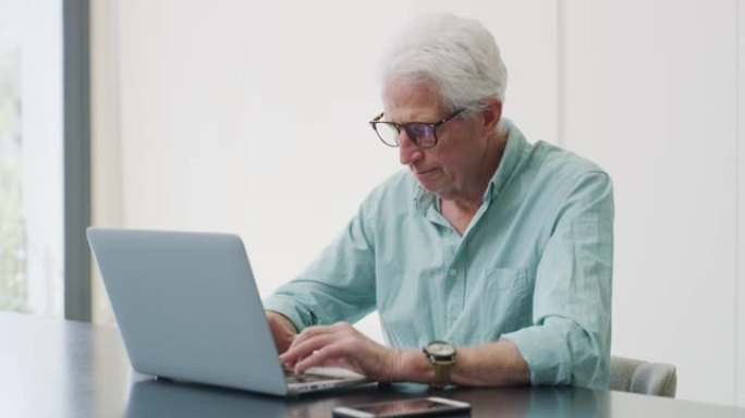 4k视频片段，一名老人在使用笔记本电脑时喝咖啡