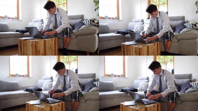 DS男子在家工作，在客厅的沙发上穿着笔记本电脑，穿着衬衫，领带和短裤