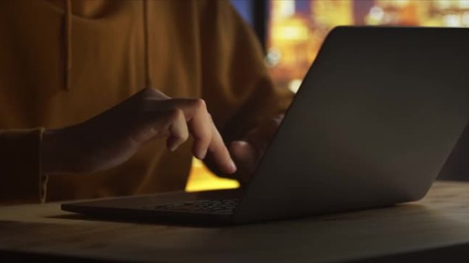 一个年轻人正在慢动作的黑色笔记本电脑上打字，