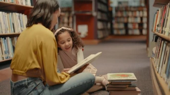 两个女人只坐在图书馆的地板上一起看书。可爱的女儿和图书馆的母亲。